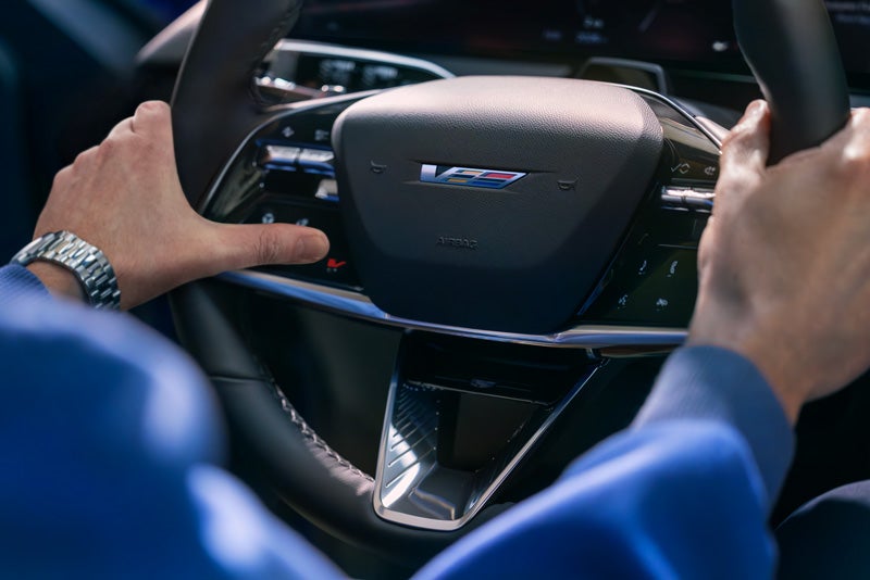 Close-up of a Man About to Press the V-Button on the 2026 OPTIQ-V Steering Wheel | Bob Johnson Cadillac in ROCHESTER NY